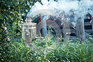 Old metal samovar on green leaves background. Samovar is using for boiling water to drink tea instead of kettle.