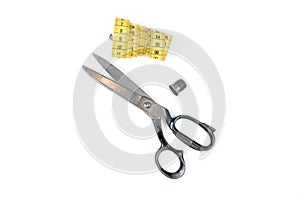 Old metal scissors and yellow measuring tape on white background