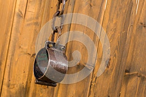 Old metal shackles closed with a chain of rings hanging on a wooden wall background