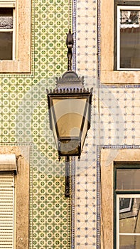 The old, metal, street lamps mounted on colorful tiled buildings in Lisbon, Portugal