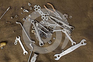 Old metal tools and screw-nuts on a dirty burlap close-up. rough surface texture