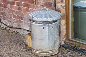 Old Metal Trash Can by a brick wall