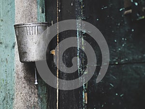 Old metal washstand is hanging on the peeling black wall