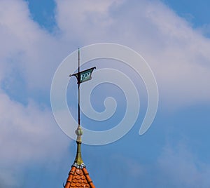 Old metal wind compass on roof with year sign 1909