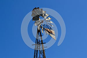 Old metal windmill with rust, in a clear blue sky. photo