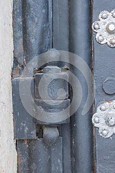 The old metal wrought-iron door is locked with a padlock. Closed metal lock.