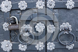 The old metal wrought-iron door is locked with a padlock. Closed metal lock.