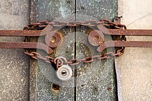 Old metallic padlock with rusty vintage chain hangs on old door