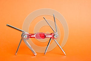 Old metallic red bike multi-tool is going to fix, repair and service on an orange background. Bicycle multifunction hand tool.