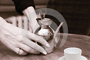 Old metallic teapot in woman's hands