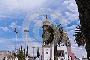 Old Mexican church and palm trees under beautiful slightly cloudy sky