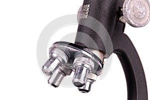 an old microscope stands isolated on a white background on a white surface