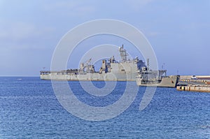 Old military battleship with radar on blue sea docked at marina