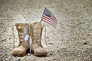 Old military combat boots with dog tags and a small American flag