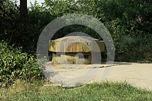 Old military green rusty iron tower with embrasures on a gray concrete pillbox