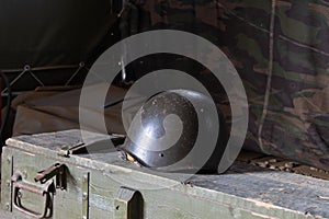 Old military helmet on the ammunition crate. Military background. War theme with helmet and military texture