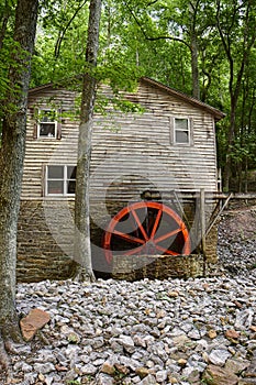 An old mill house with a bright red millwheel