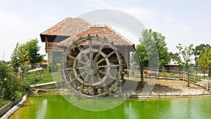 Old mill with a large wooden wheel in a landscaped tourist environment