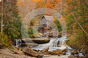 Old mill situated behind a waterfall surrounded by autumn foliage New River Gorge National Park