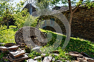 Old millstone in a meadow next to stone houses, black villages, Majaelrayo. photo