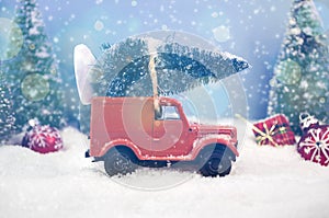 Old miniature truck or oldimer with a christmas tree on the roof driving trough a winterly landscape with some kind of christmas d photo