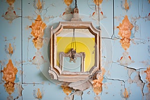 an old mirror hanging askew on a peeling wallpaper wall