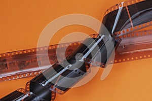 Old 35 mm Photographic film strips, negative on bright orange background, flat lay. Photo, movie cinema concept