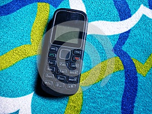 Old Mobile Phone with Texting or SMS Button Keyboard or Keypad on Colorful Carpet Background