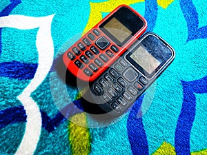Old Mobile Phone with Texting or SMS Button Keyboard or Keypad on Colorful Carpet Background