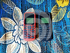 Old Mobile Phone with Texting or SMS Button Keyboard or Keypad on Colorful Flowery Fabric Background