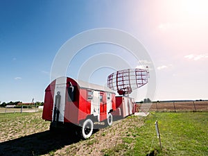 Old mobile radar station painted in red and white color. Blue sky background. Airport space control and coordination. Modern