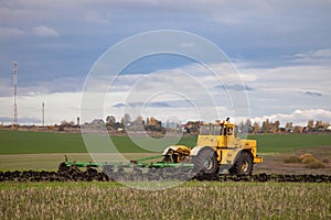 old model tractor working in the field.