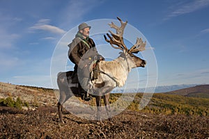 Old Mongolian man riding a reindeer.