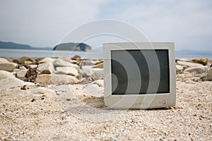 Old monitor on the rocky beach.
