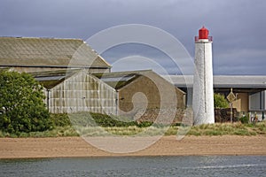 The Old Montrose Rear Lighthouse next to the Beach and beside some Old Warehouses with Galvanised Sides and Roofs.