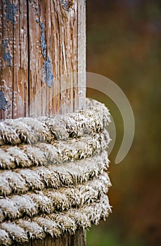 Old mooring rope wrapped on a wooden pole while holding the moored vessel