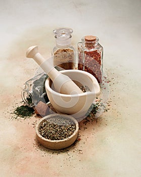 Old mortar and pestle with spices and herbs on softly colored canvas