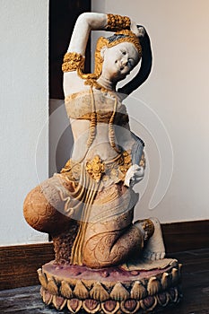 Old mortar statue of woman wearing thai dress kneeling on the lotus at the home, Vintage