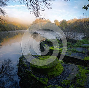 Old moss covered millstones on the bank of the Mino river