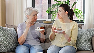 Old mother and adult daughter eating cake at home