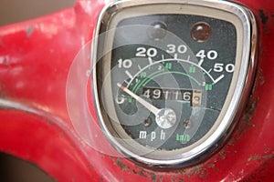 Old motor bike meter close-up shot.Scooter scratched speedometer closeup view.Speedometer dial on a red old scooter or moped