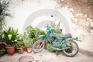 Old motorbike parked against a rustic wall