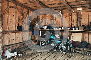 Old Motorbike In A Picturesque Barn. Vintage Motorcycle In Old Hangar With Many Rare Objects