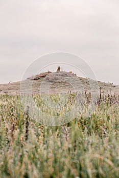 Old mound on hill in autumn. Dawn in autumn field. Hills in morning haze. Grass covered with autumn hoarfrost. Nature