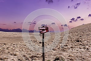 Old mountain crossroads signpost and colorful sunset sky