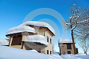 Old mountain houses half-buried by falling snow