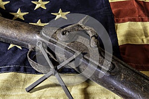 Old musket rifle and metal cross on American flag