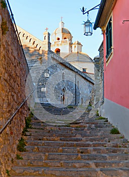 Old narrow stone street and stairs with church in background in Portovenere  town. Lord Byron Park and Doria castle on Ligurian co