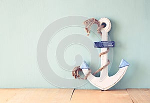 Old nautical anchor on wooden table over wooden aqua background