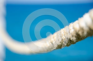 Old nautical cord. Sea background with copy space. Selective focus on rope texture on blurred sea surface background. Stretched